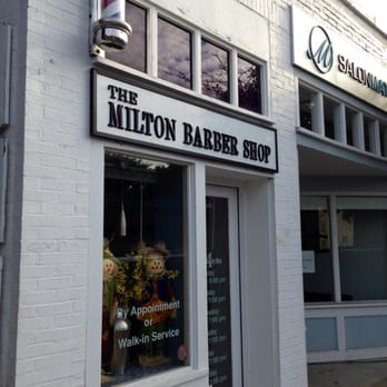 The Milton Barber Shop storefront on Adams Street — white brick, black sign, barber pole by the door